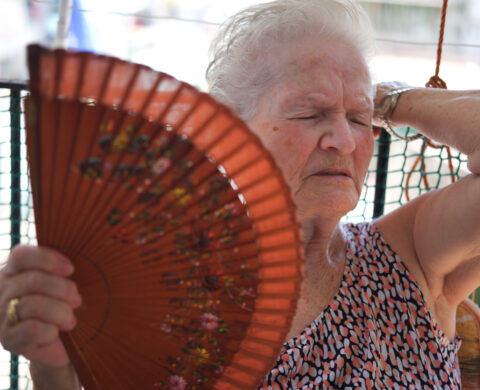 Poor Elderly Woman Using A Fan To Refresh Herself